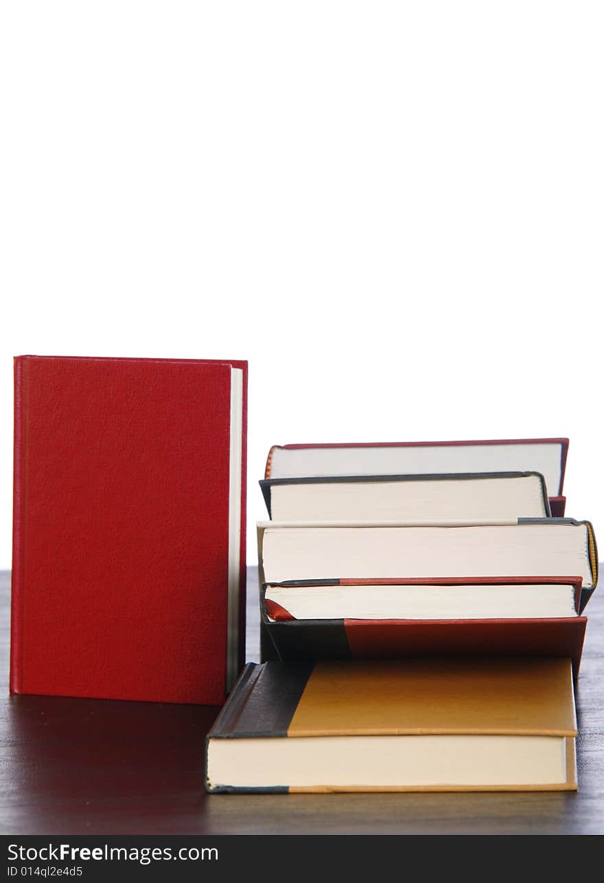 A red book standing near a stack of books isolated against white. A red book standing near a stack of books isolated against white.