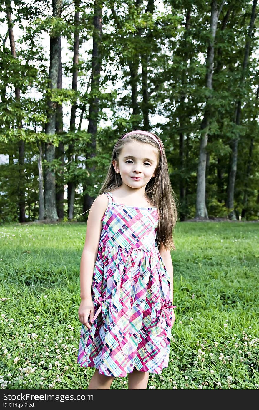 Beautiful young girl dressed in a plaid sundress in an outdoor setting. Beautiful young girl dressed in a plaid sundress in an outdoor setting.