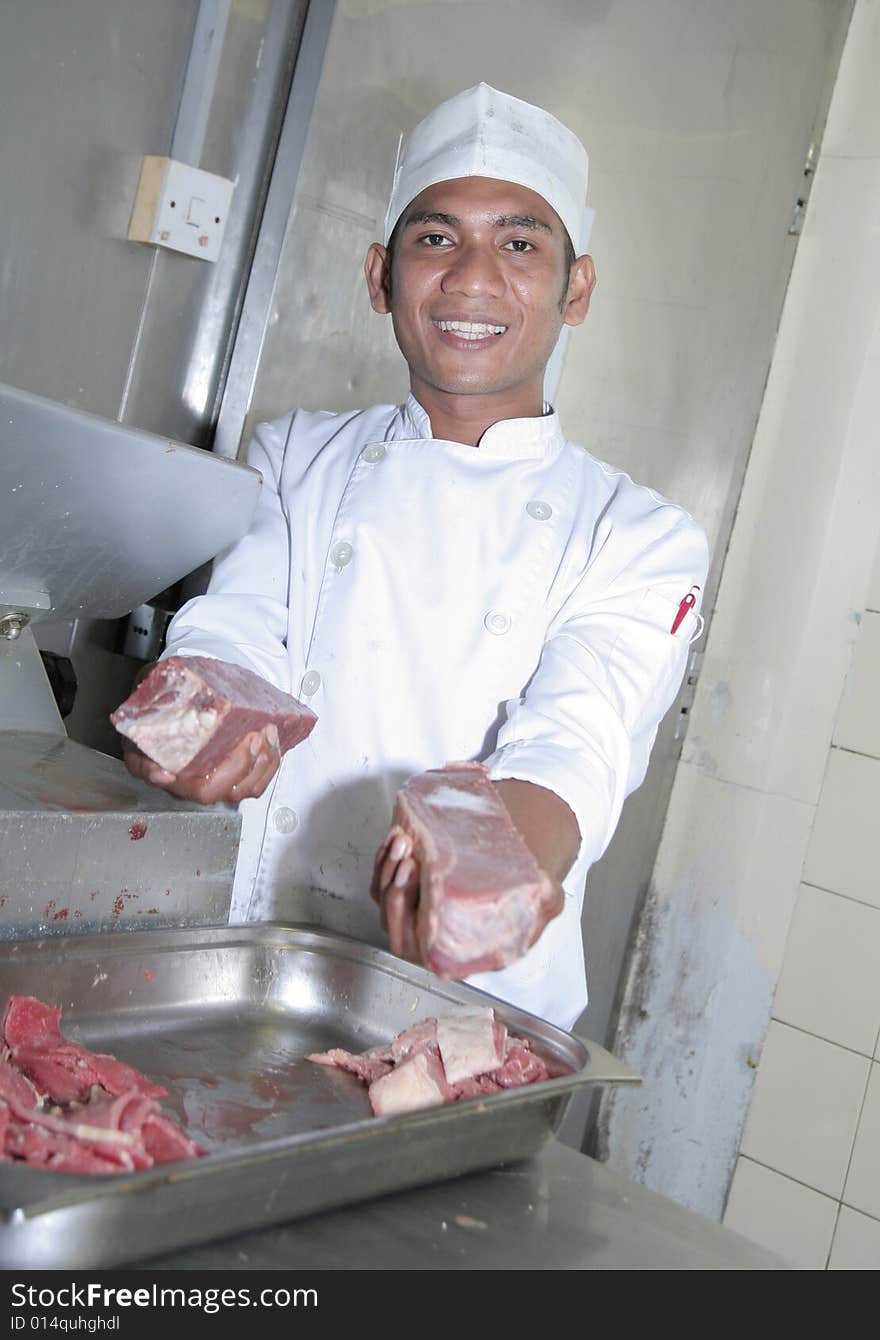 Chef at butcher, cutting meats with cutting machine