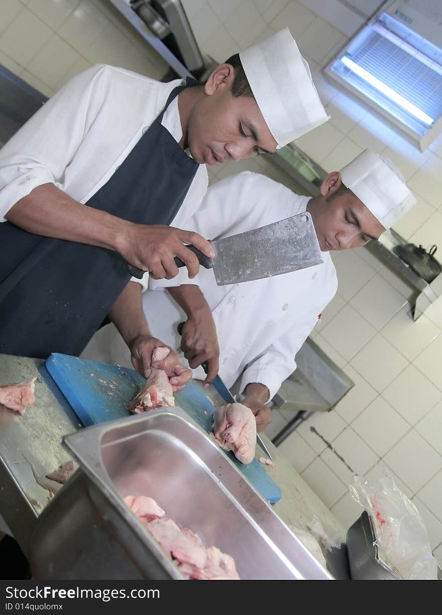 Two chefs butchering chicken meat. Two chefs butchering chicken meat