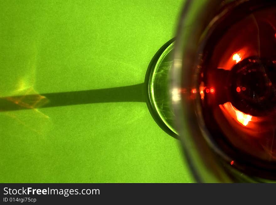 A glass of red wine on a green background taken from an unusual perspective. Cheers!. A glass of red wine on a green background taken from an unusual perspective. Cheers!