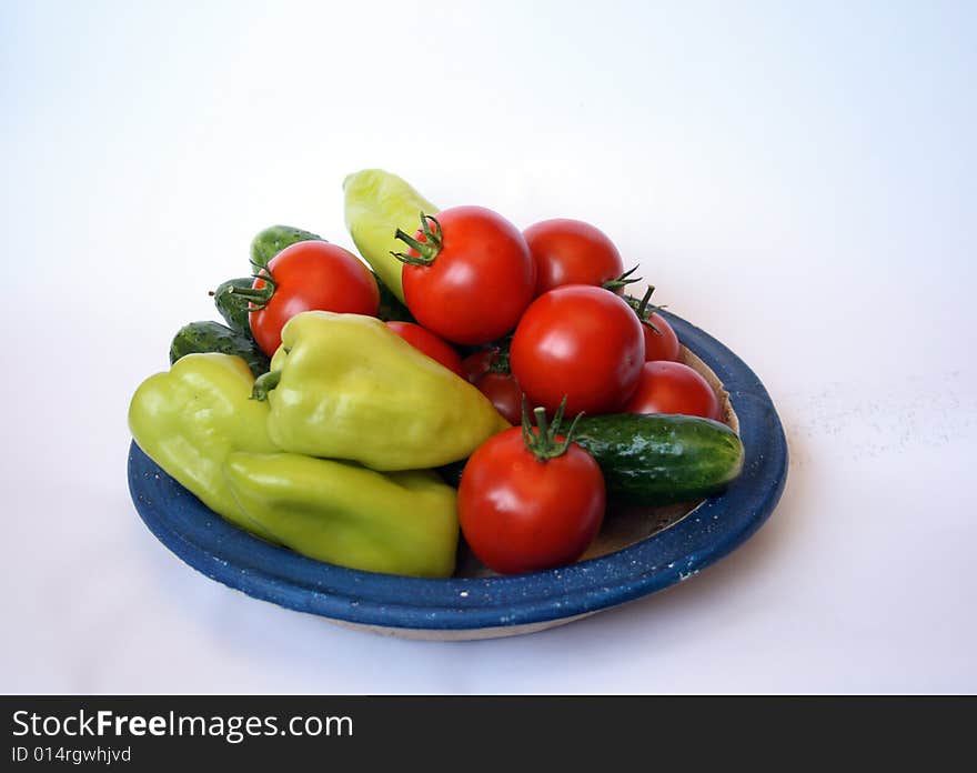 Fresh tomato, sweet peper and cucumber on country style plate isolated on white background