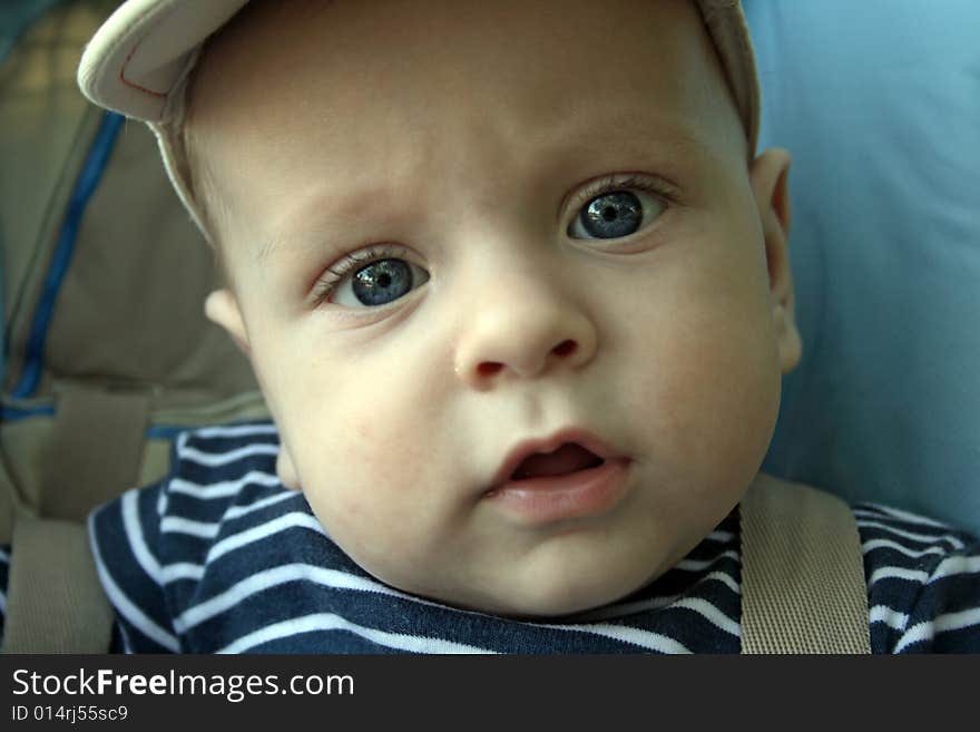 The little boy looks out through cot rods. The little boy looks out through cot rods