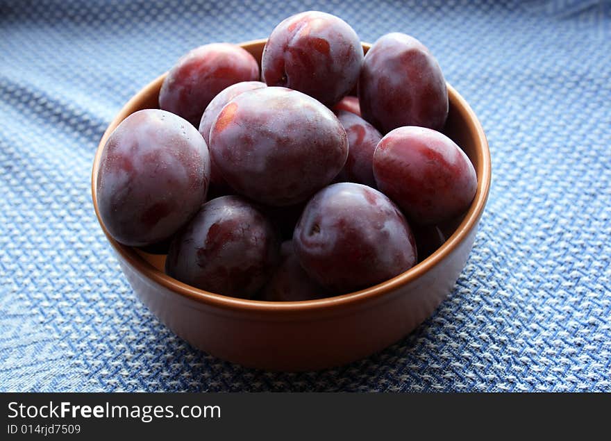 Plums on plate on Blue cloth