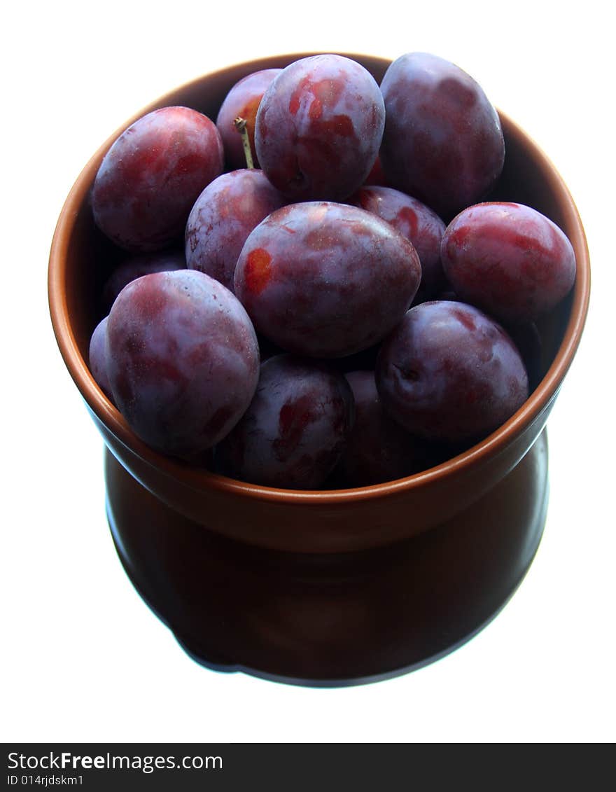 Plums on plate in the mirror isolated on white background