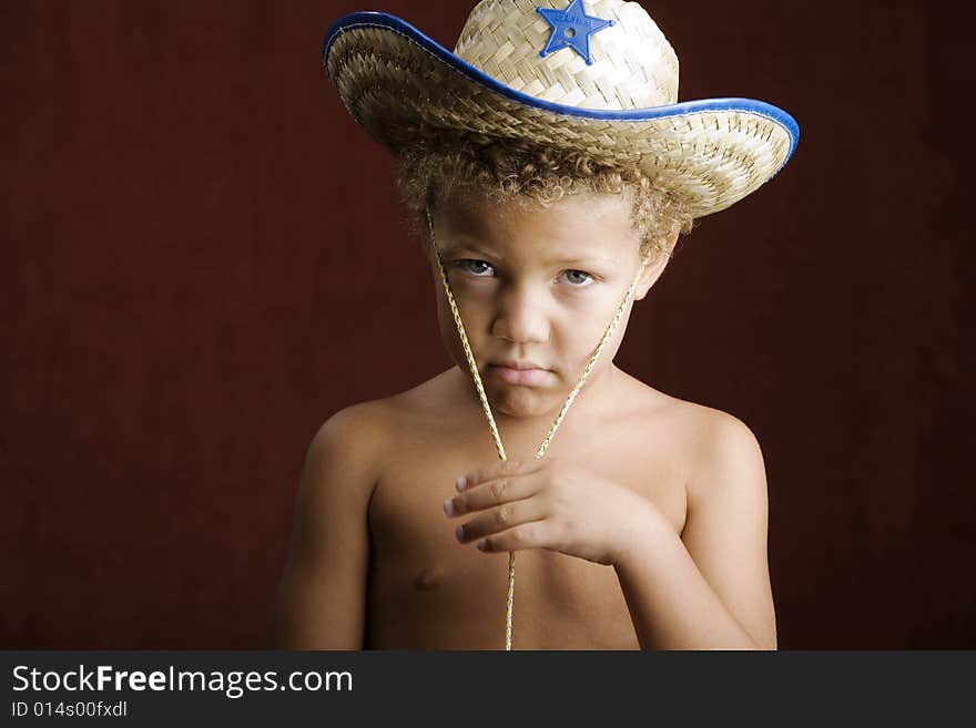 Little boy with curly hair and blue eyes in a sheriff hat. Little boy with curly hair and blue eyes in a sheriff hat