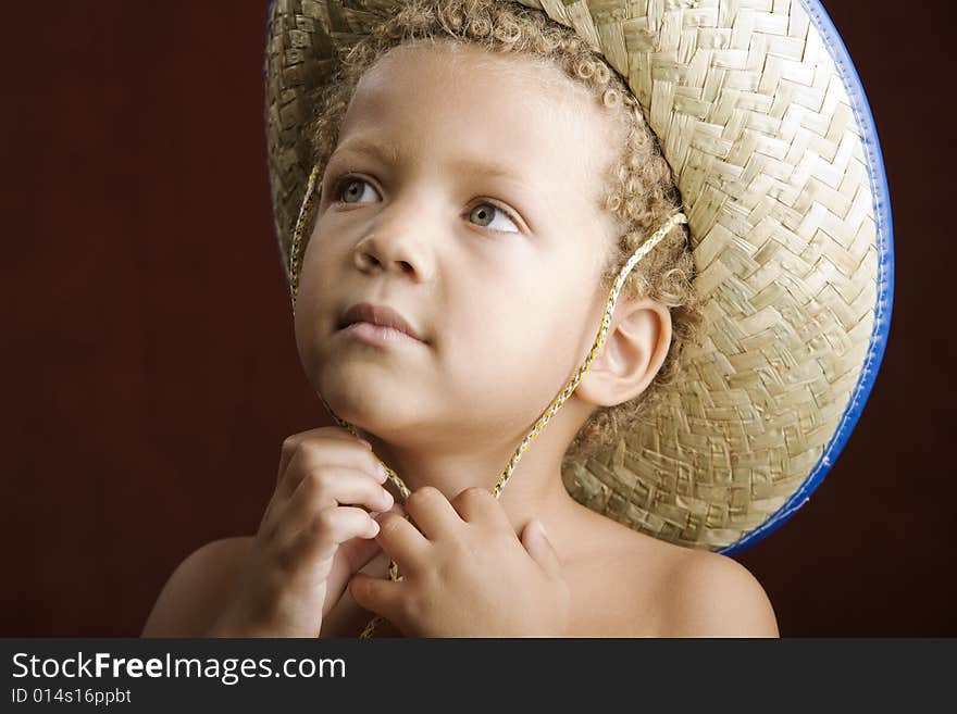 Little boy with curly hair and blue eyes in a straw hat. Little boy with curly hair and blue eyes in a straw hat