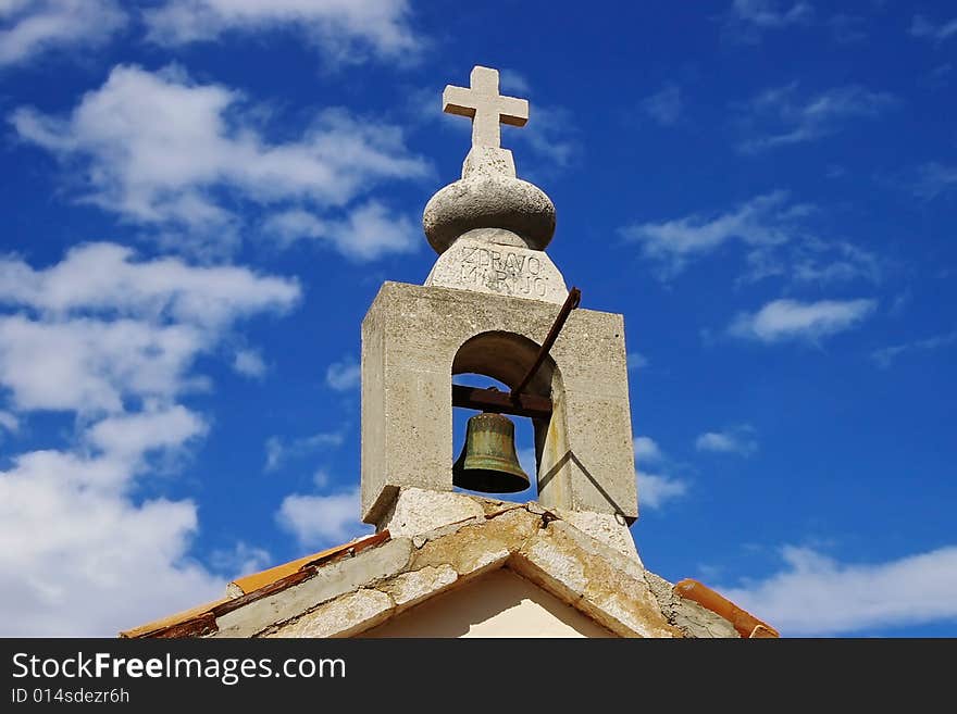 Belltower on a background of the blue sky with a clouds.