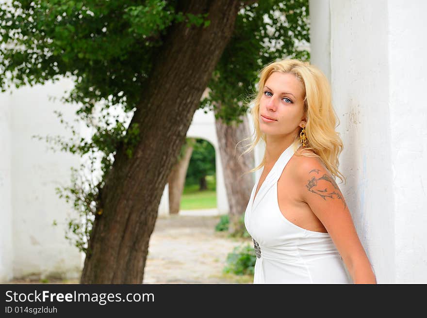 Blond woman in white dress against white wall. Blond woman in white dress against white wall