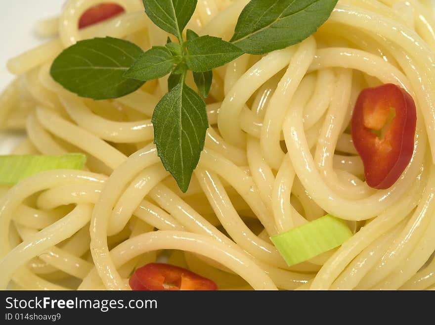 Spaghetti with garnishing of fresh basil leaves.