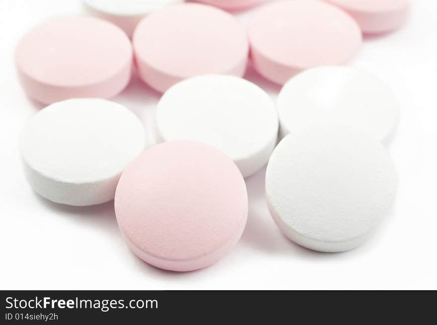 Pink and white tablets and pills isolated on white