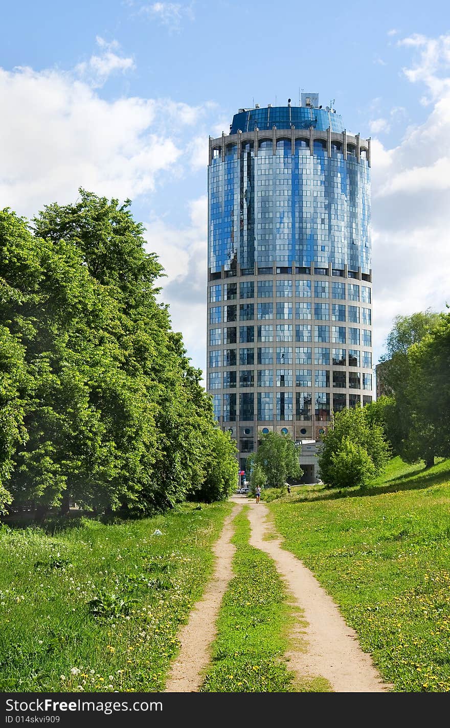 A dirt unsurfaced road contrasting with a modern-style highrise building. A dirt unsurfaced road contrasting with a modern-style highrise building