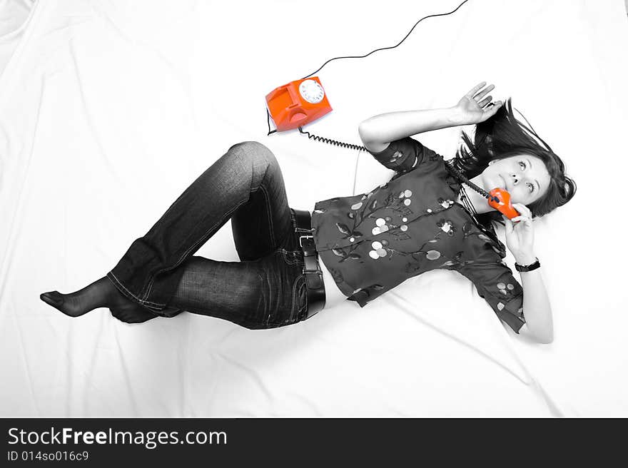 Pretty girl laying on the floor and  talking by orange phone. Pretty girl laying on the floor and  talking by orange phone