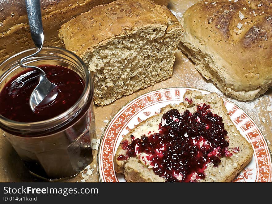 Slice of freshly made grainy bread, with country style plate and board, home made preserve, butter and jam spoon. Slice of freshly made grainy bread, with country style plate and board, home made preserve, butter and jam spoon