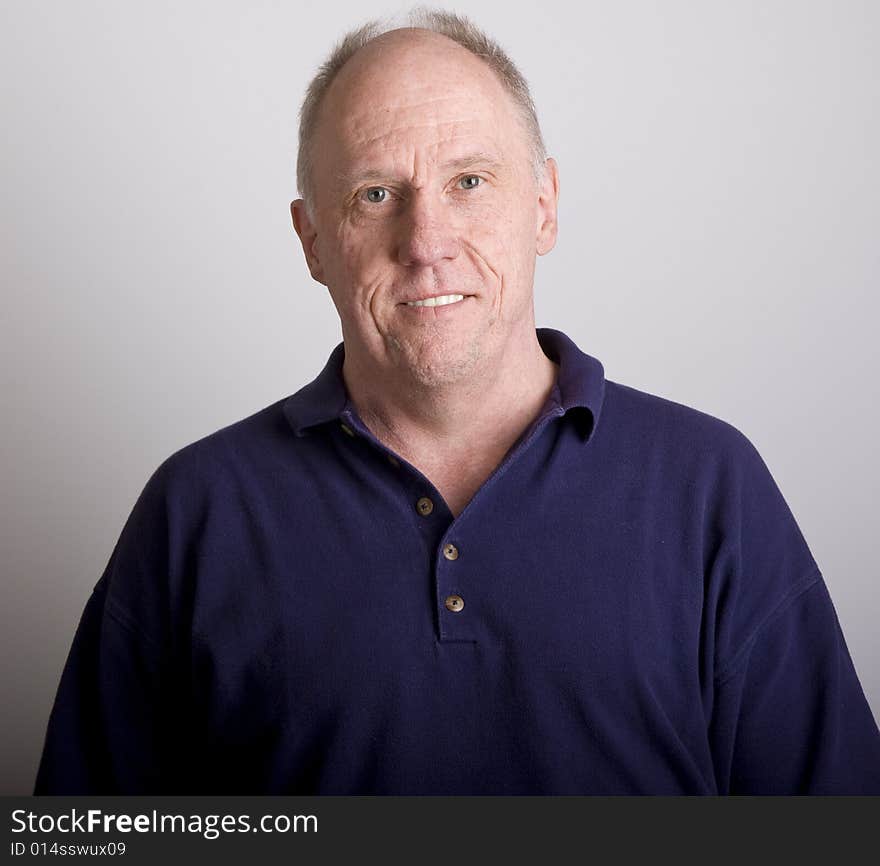 An older bald guy in blue shirt smiling. An older bald guy in blue shirt smiling