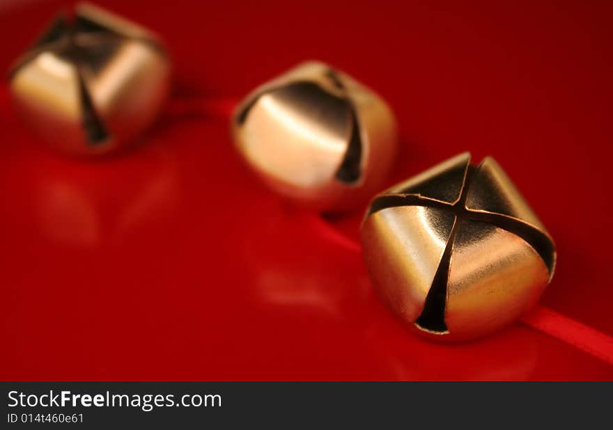 Three gold bells with red ribbon on a red background. Used a shallow depth of field and selective focus. Three gold bells with red ribbon on a red background. Used a shallow depth of field and selective focus.