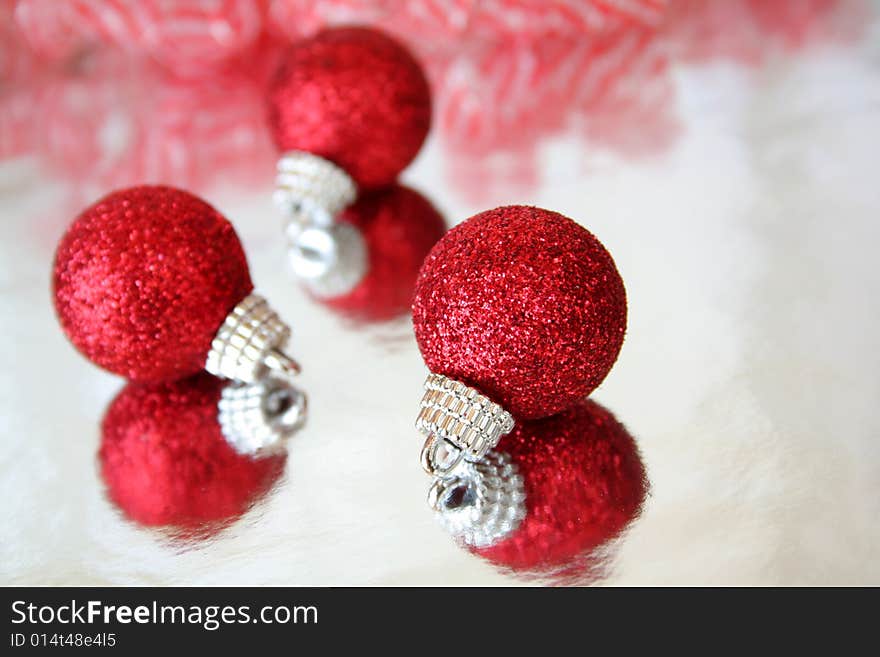 Red Christmas ornaments on a reflective surface. Copy space available.