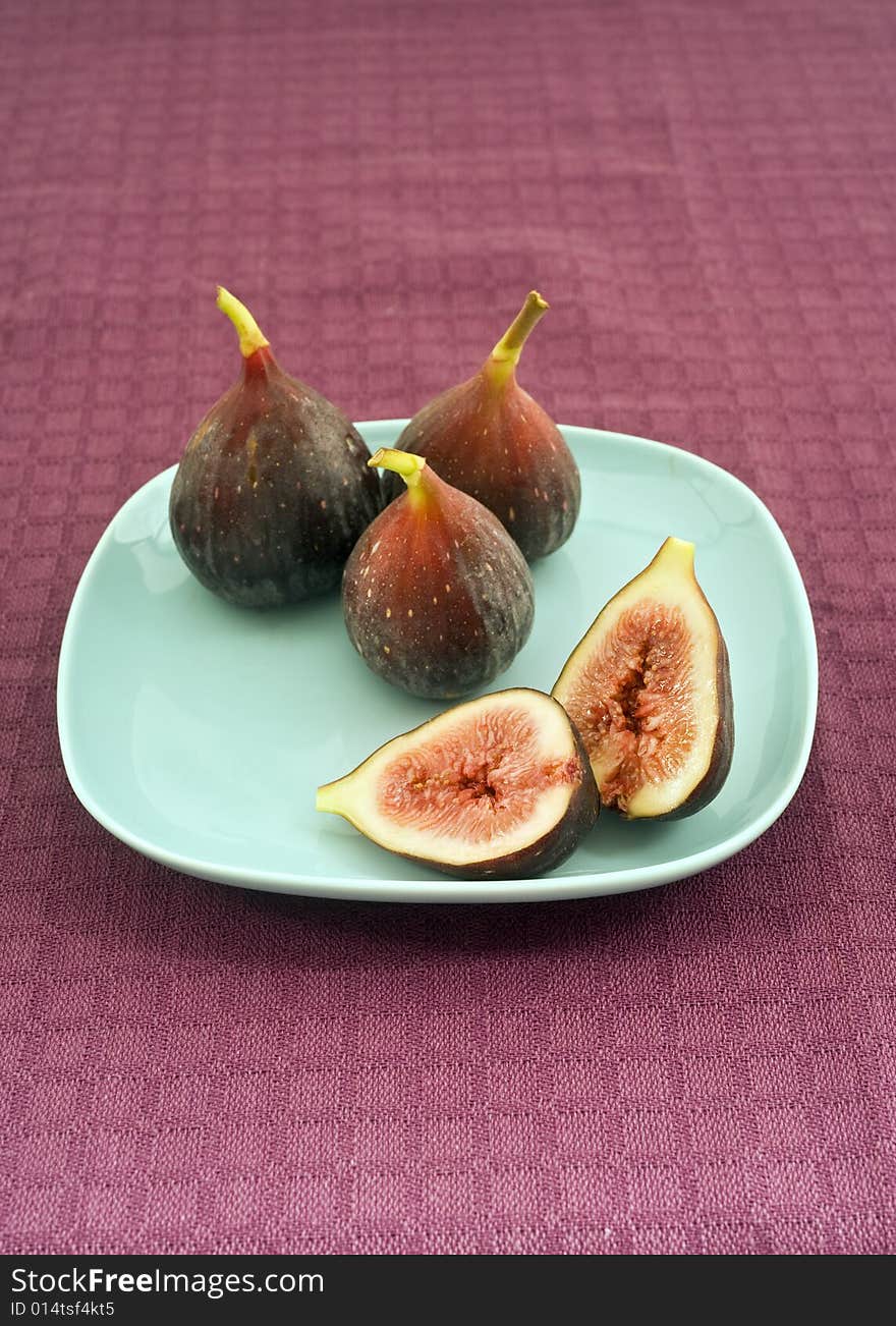 Still life three whole figs and one sliced on blue plate. Still life three whole figs and one sliced on blue plate