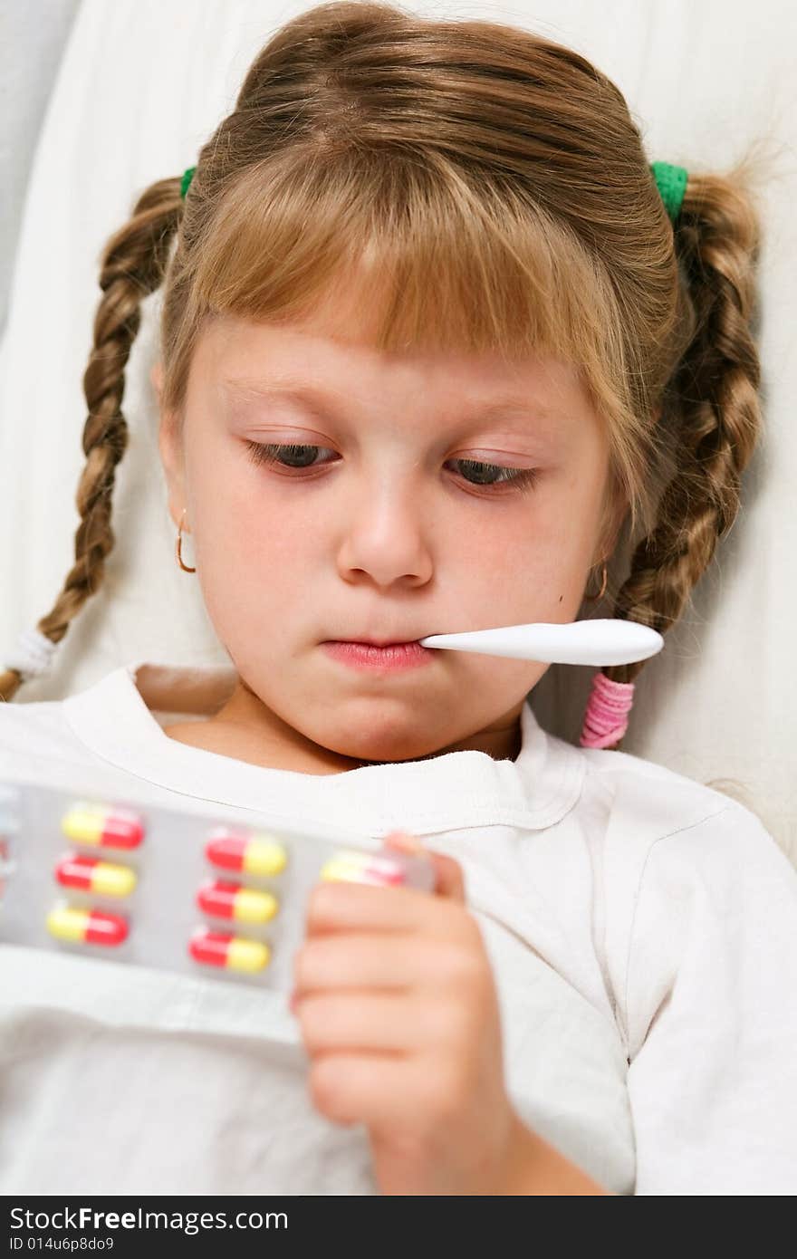 Young girl in bed with thermometer in mouth