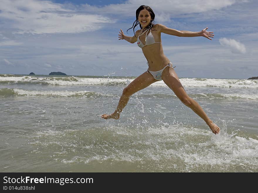 Female teenager jumps on the beach