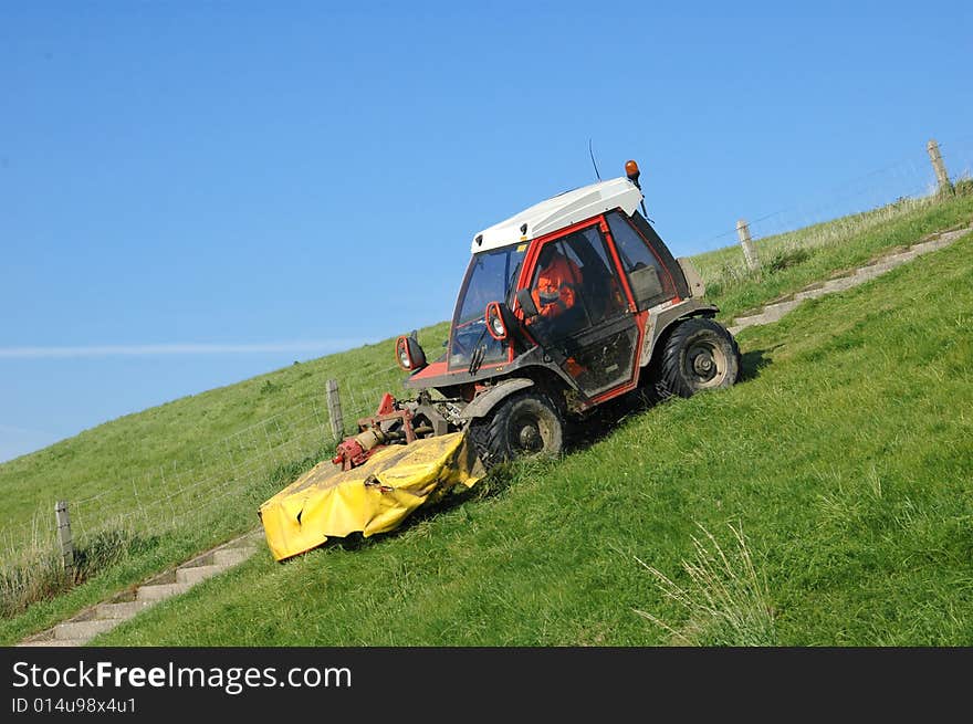 Tractor lawnmower mowing the grass riding down a. Tractor lawnmower mowing the grass riding down a