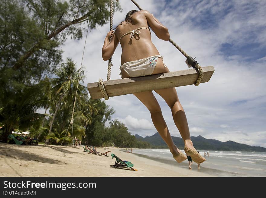 Girl on swing on the beach enjoys the vacation