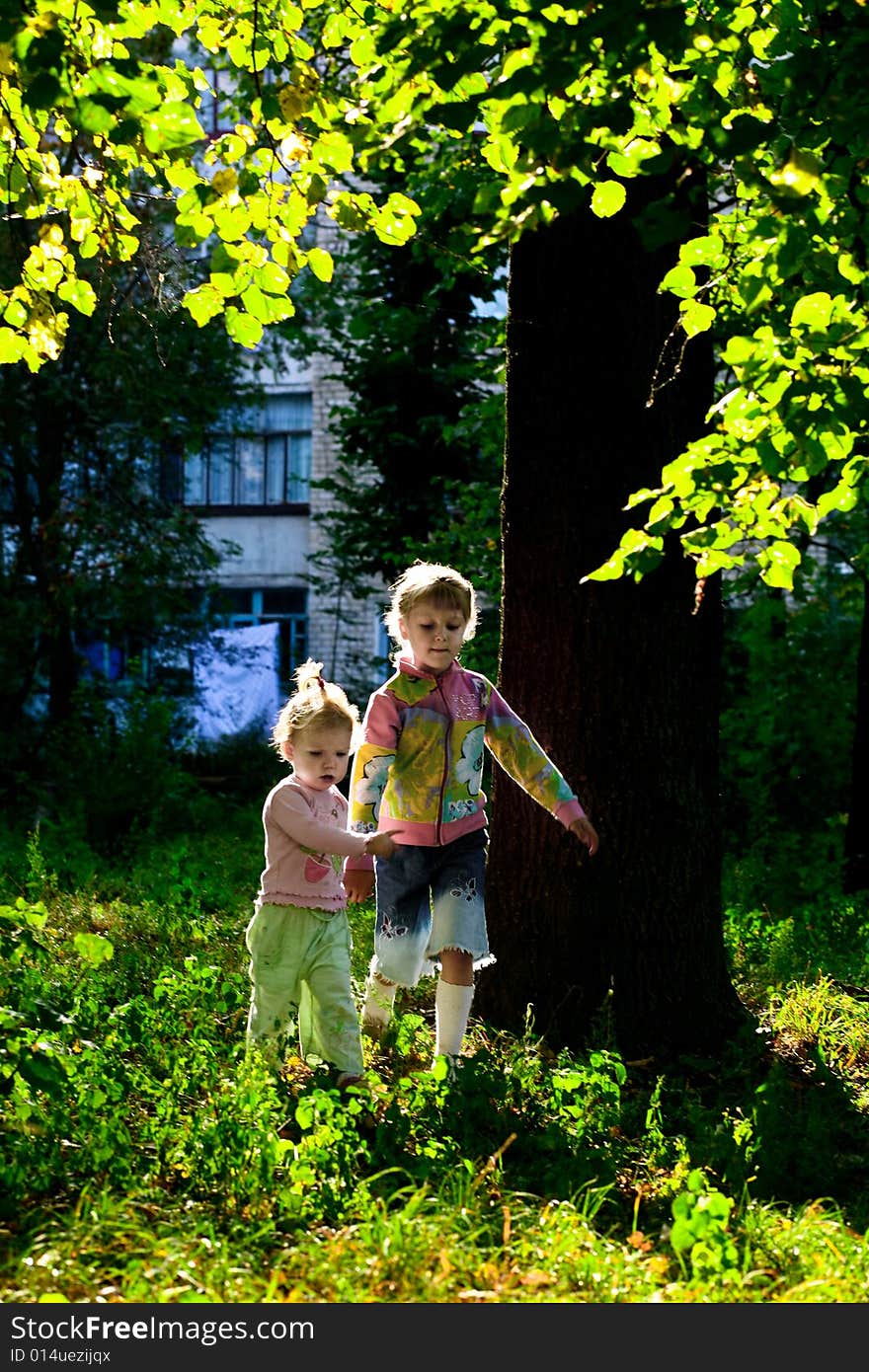 An image of two sisters walking amongst green trees