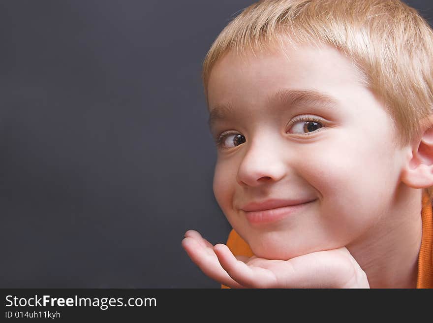 Friendly boy with an orange shirt against a black background