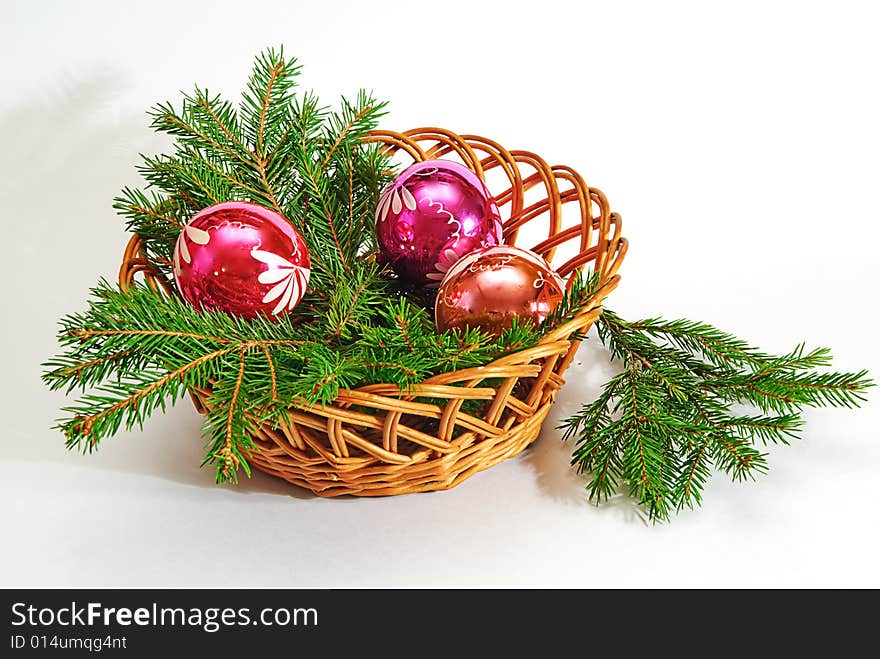 Green fir tree twig and three red ball in basket. Green fir tree twig and three red ball in basket