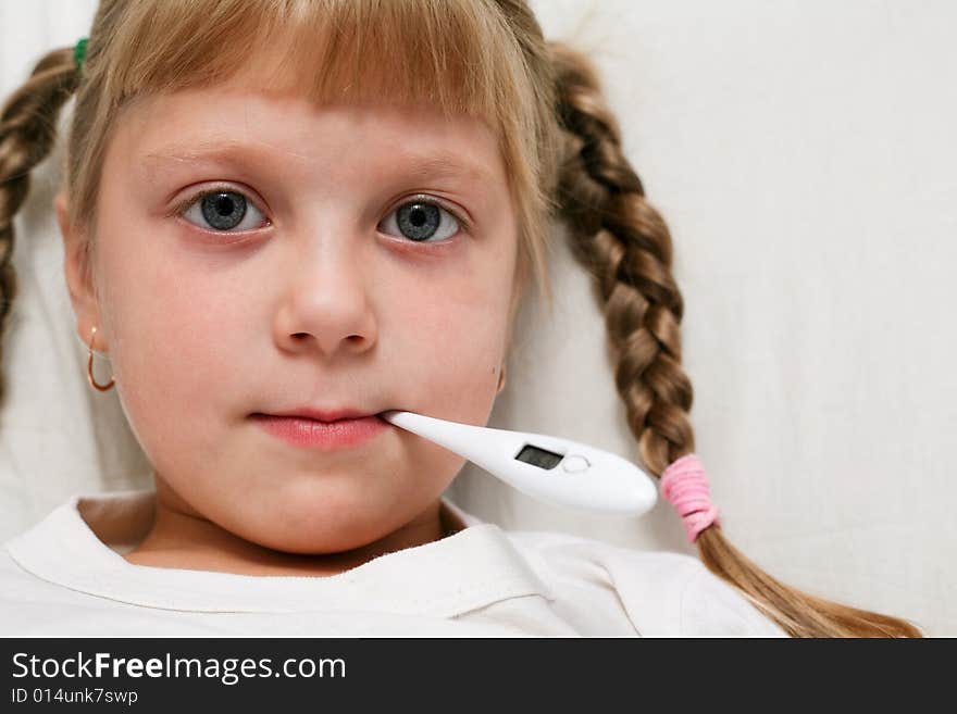 Sick child in bed under blanket with thermometer in mouth. Sick child in bed under blanket with thermometer in mouth