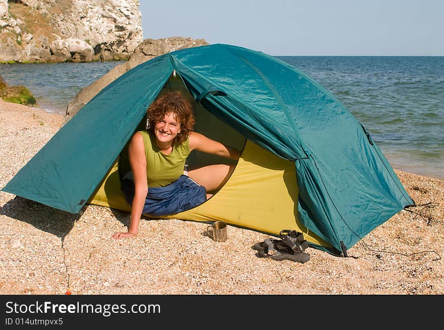 Smiling girl looking from a tent at seaside. Smiling girl looking from a tent at seaside