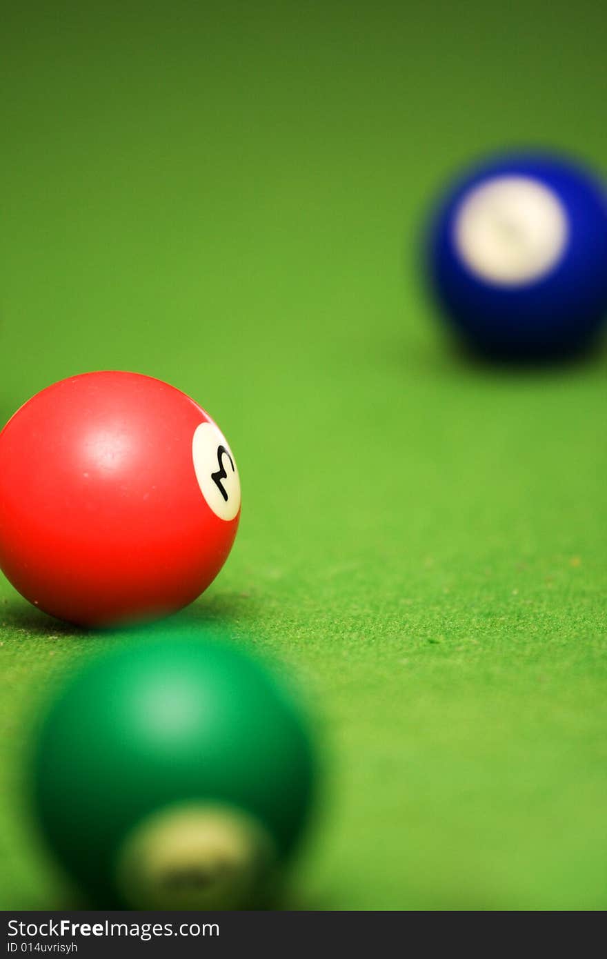 Three pool balls on a green pool table. Focus on middle ball. Three pool balls on a green pool table. Focus on middle ball.