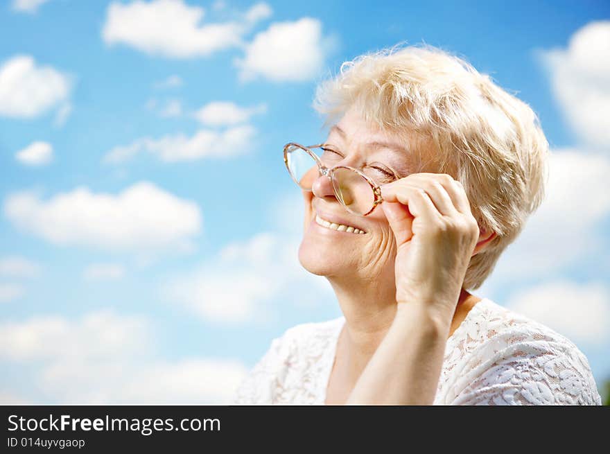 Portrait of the laughing elderly woman with glasses against the sky. Portrait of the laughing elderly woman with glasses against the sky