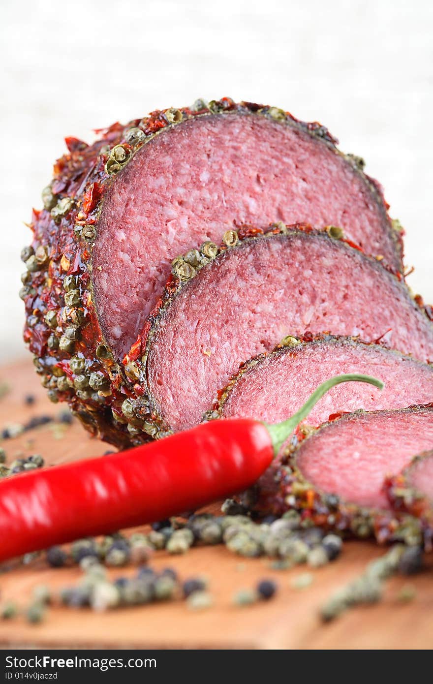 Slices of salami with pepper grains and chili