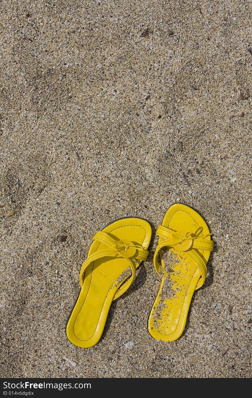 Yellow flip-flops on sand