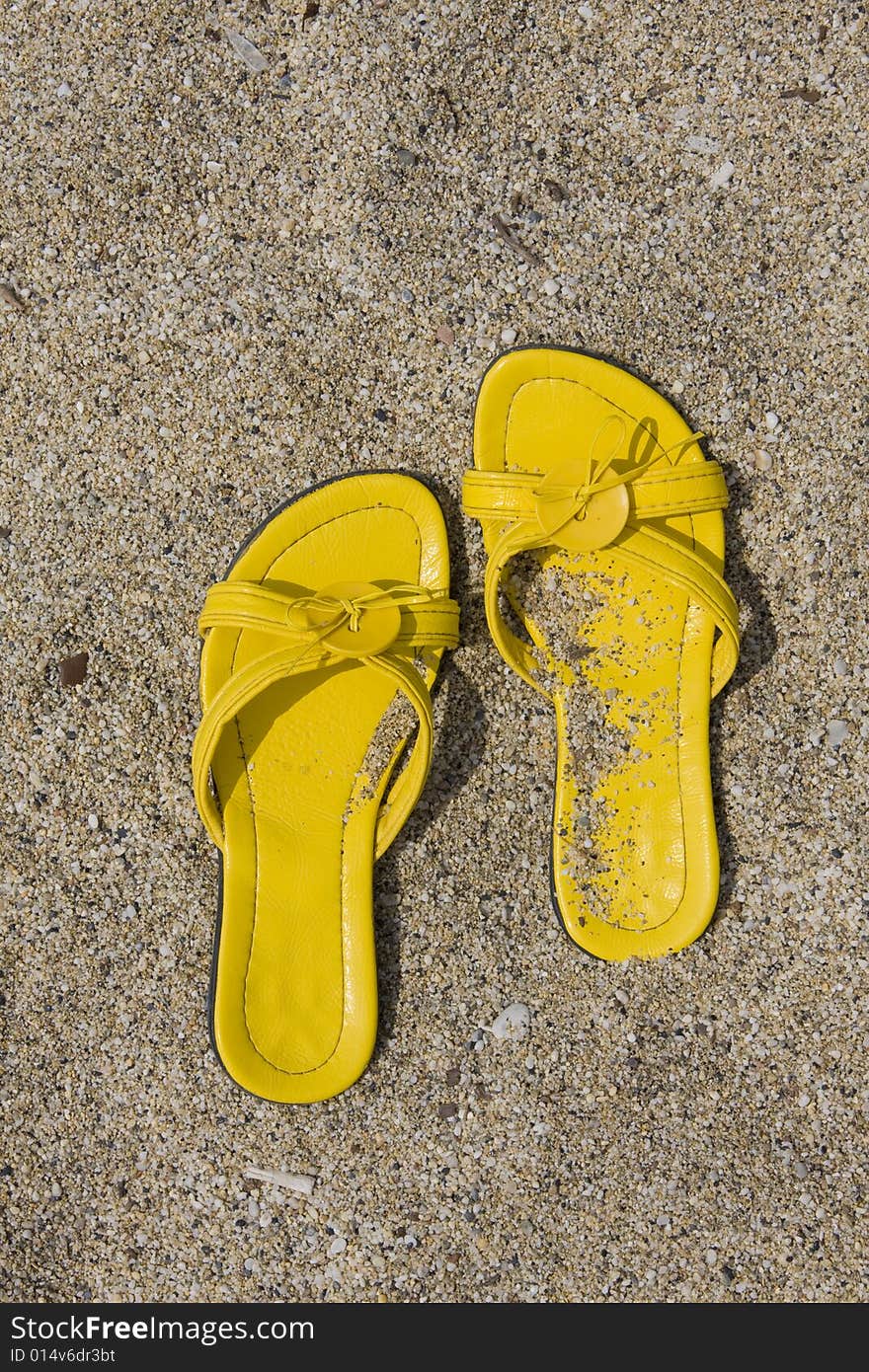 Yellow flip-flops on sand