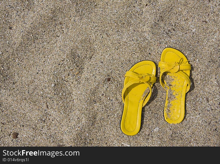 Yellow flip-flops on sand