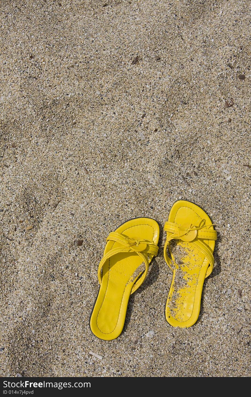 Yellow flip-flops on sand