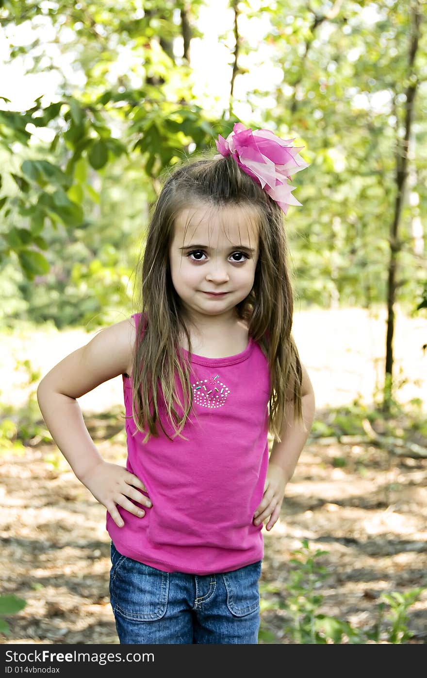 Beautiful child wearing a pink bow and shirt in an outdoor setting. Beautiful child wearing a pink bow and shirt in an outdoor setting.