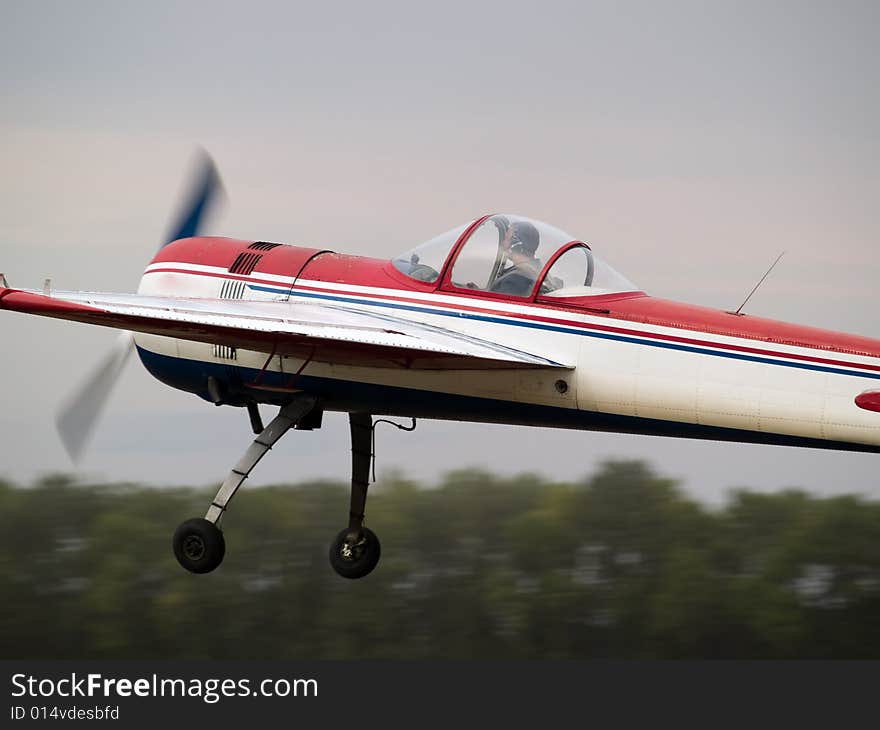 Small aerobatics plane performing speed pass low altitude. Small aerobatics plane performing speed pass low altitude