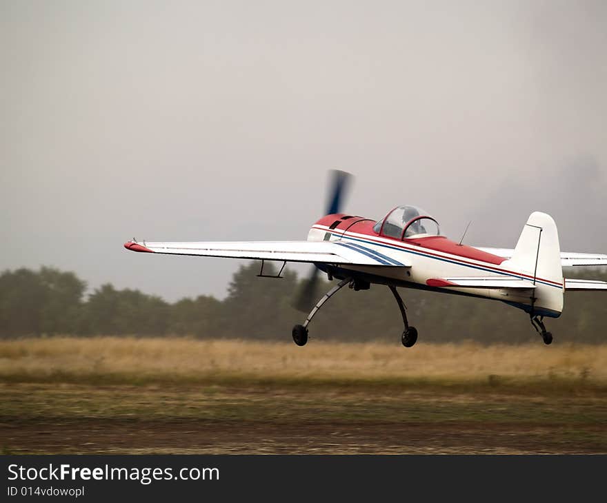 Small aerobatics plane landing on dirt runway. Small aerobatics plane landing on dirt runway