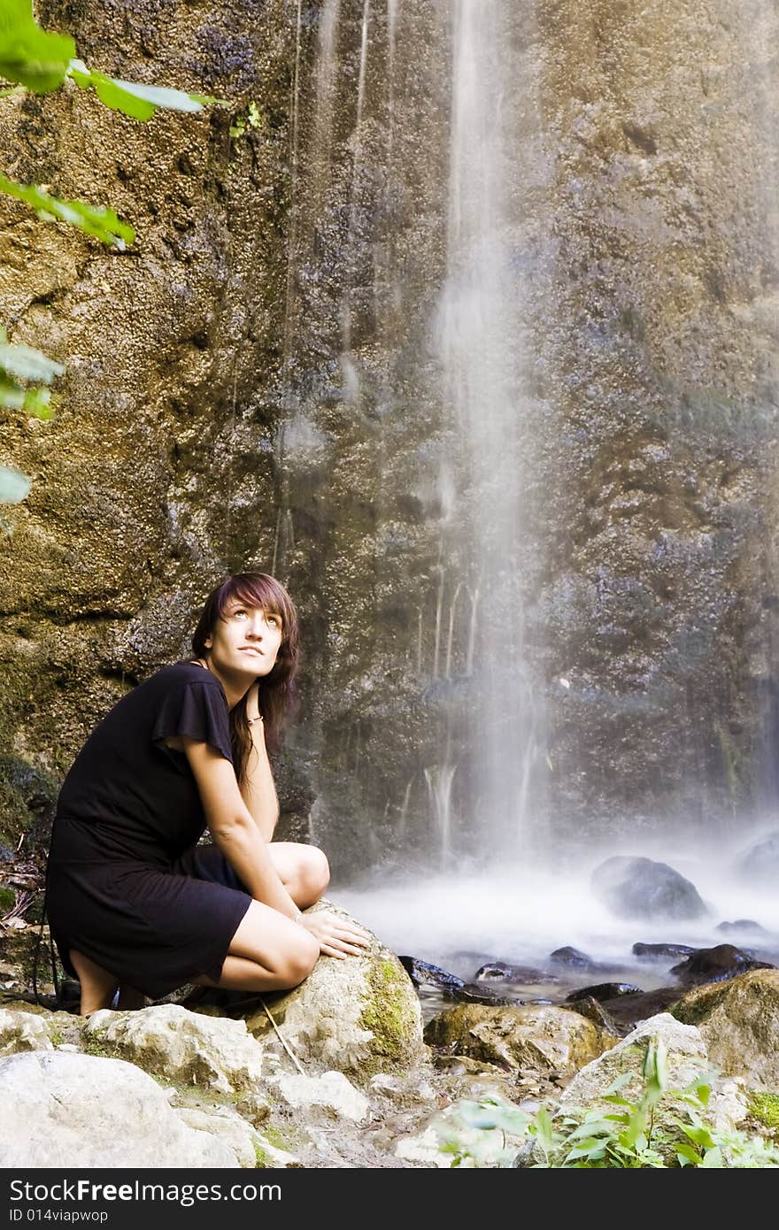 Young woman posing under long exposed waterfall. Young woman posing under long exposed waterfall