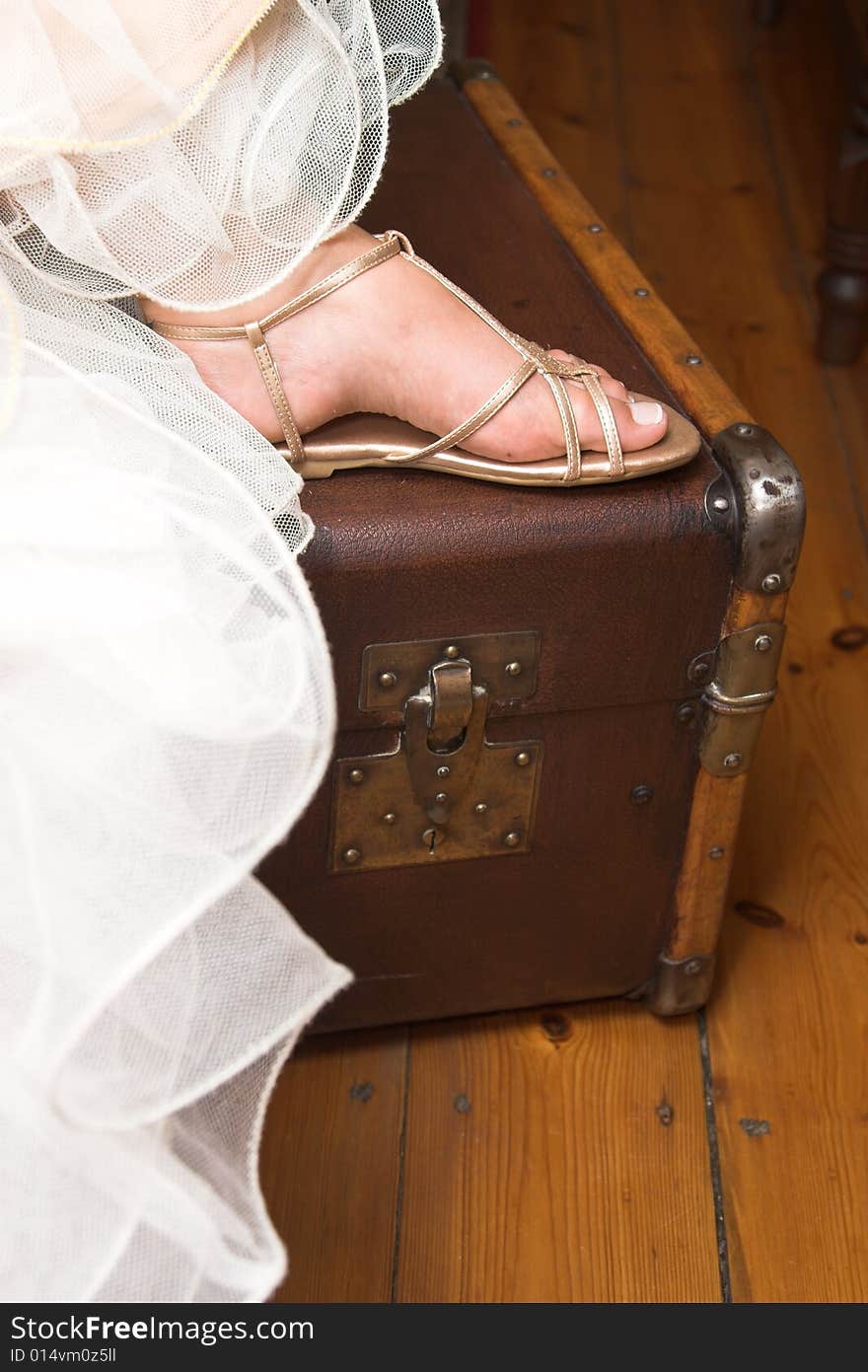 Young bride sitting with her foot on a suitcase