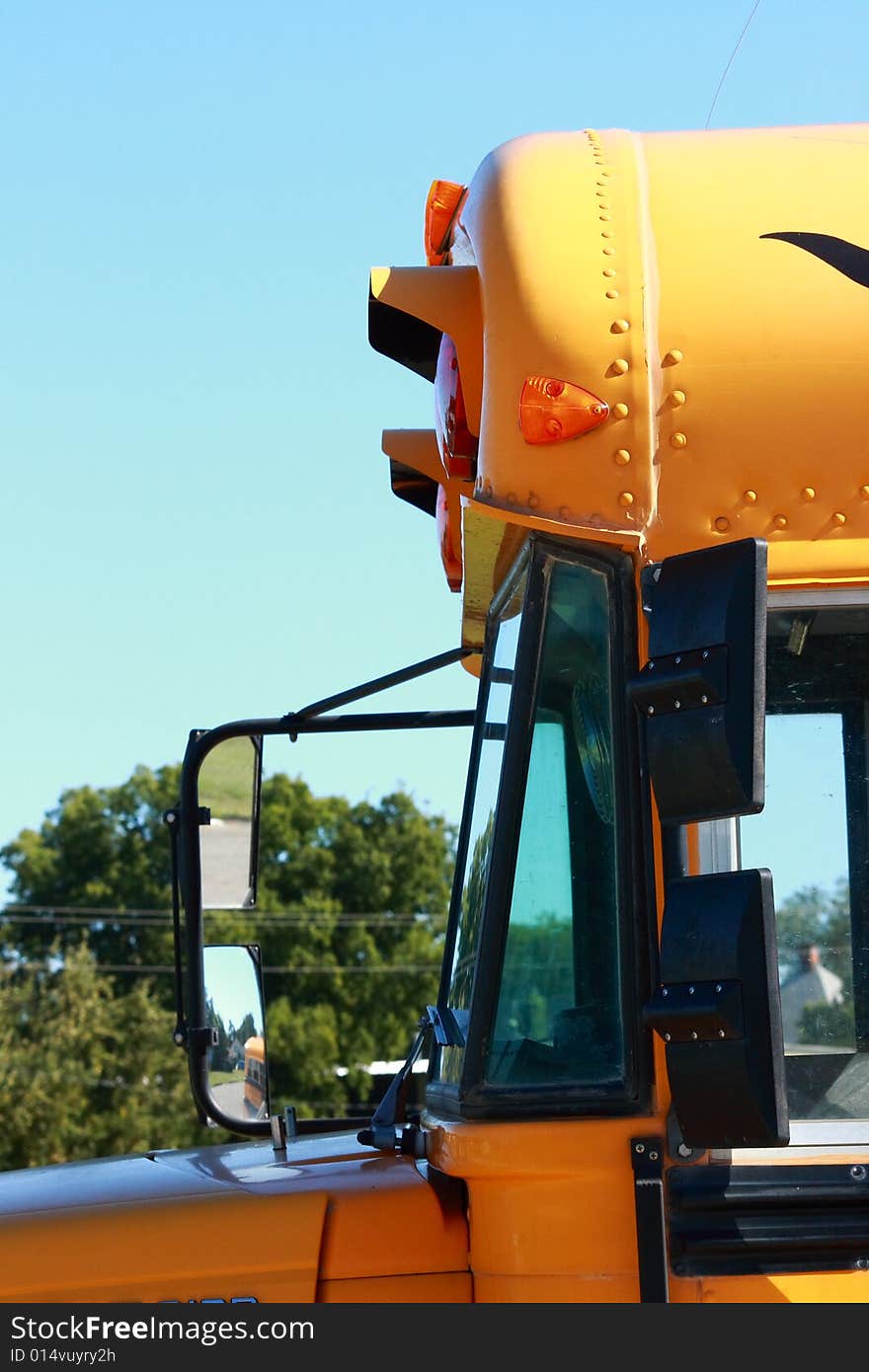 Side view of the front end of a yellow school bus showing some reflection in the side view mirrors. Side view of the front end of a yellow school bus showing some reflection in the side view mirrors.