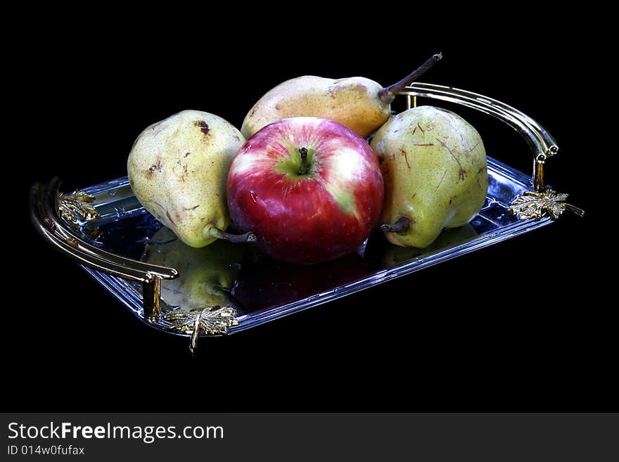 Pears and apple on tray on black background