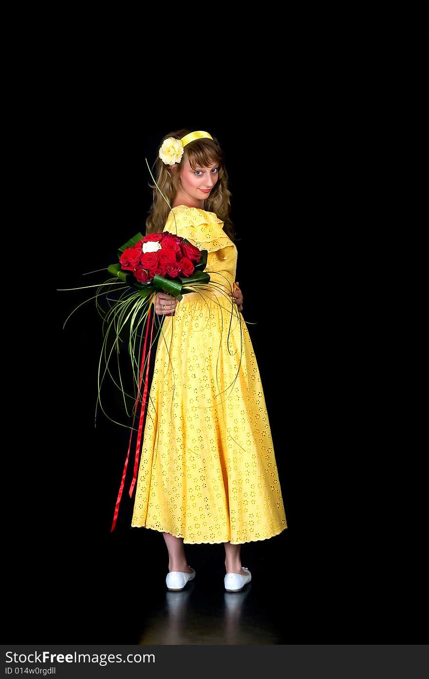 Portrait of a beautiful young bride showing her wedding bouquet of red and white roses on black background, studio shot. Portrait of a beautiful young bride showing her wedding bouquet of red and white roses on black background, studio shot