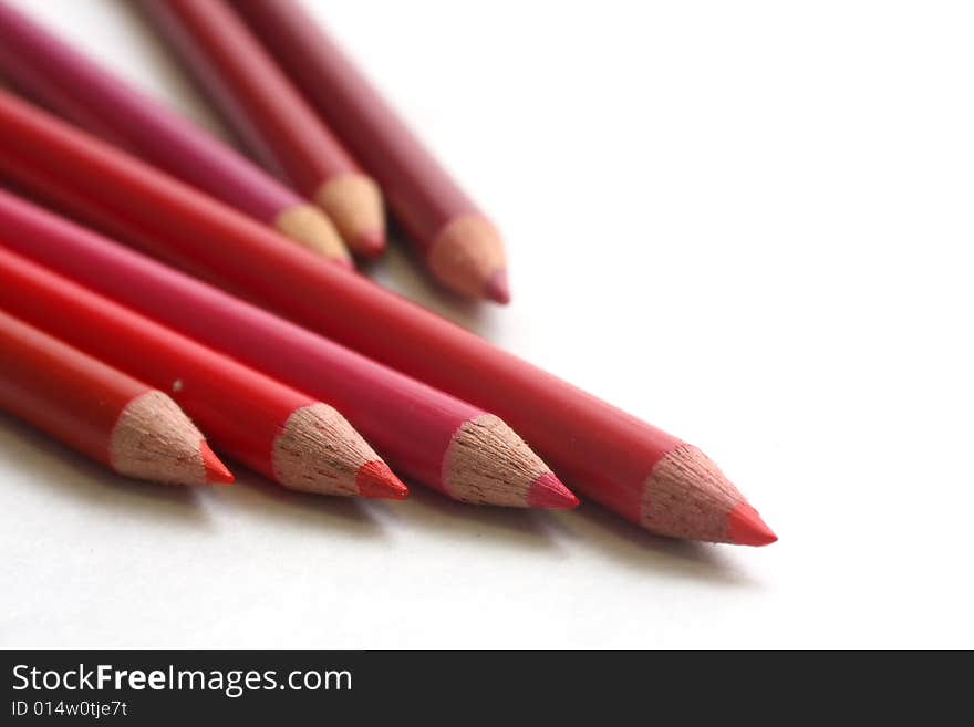 Different hues of red coloring pencils on white