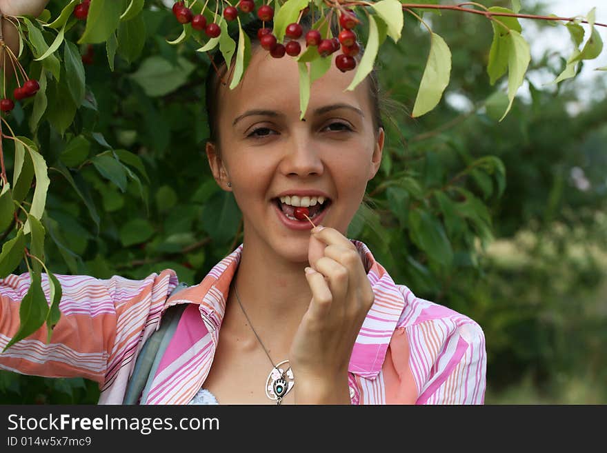 Portrait of girl with a berry on a background greenery