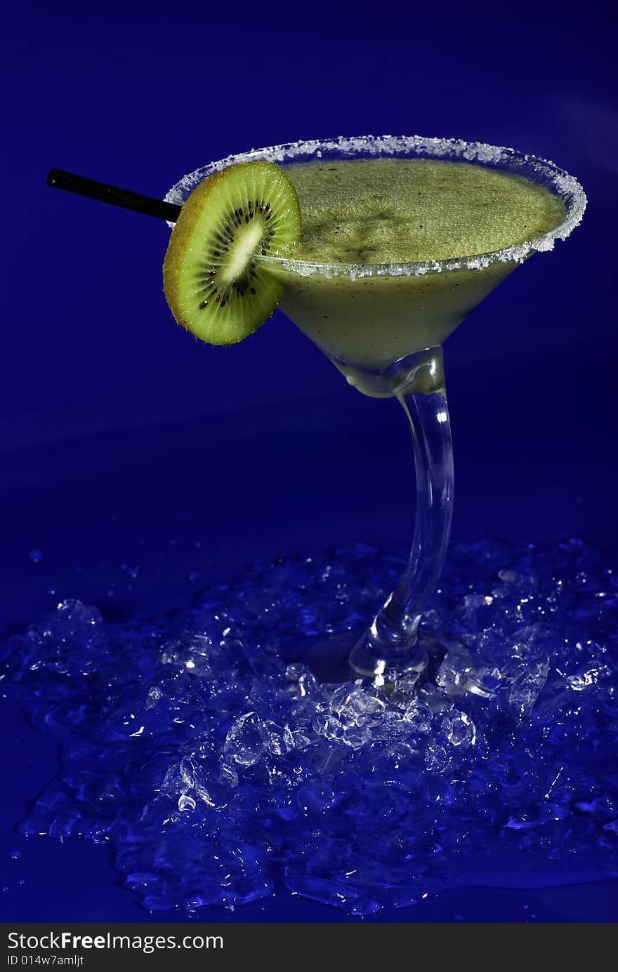 Green cocktail with foam, kiwi on blue background. Green cocktail with foam, kiwi on blue background