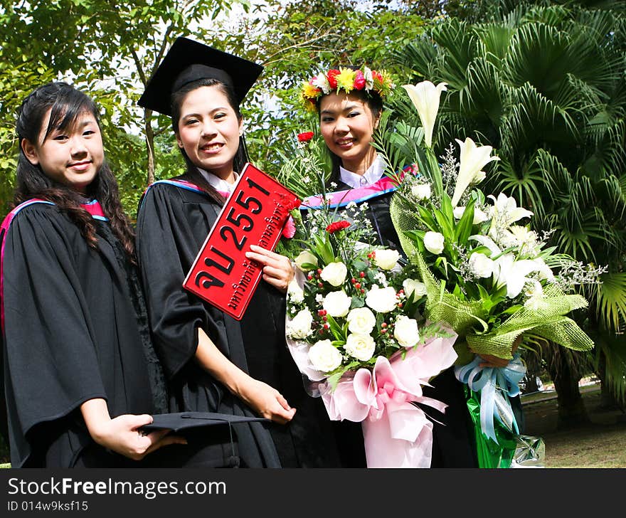 Gorgeous Asian university graduates celebrating their success. Number plate says Happy Graduation in Thai and the number refers to this year.